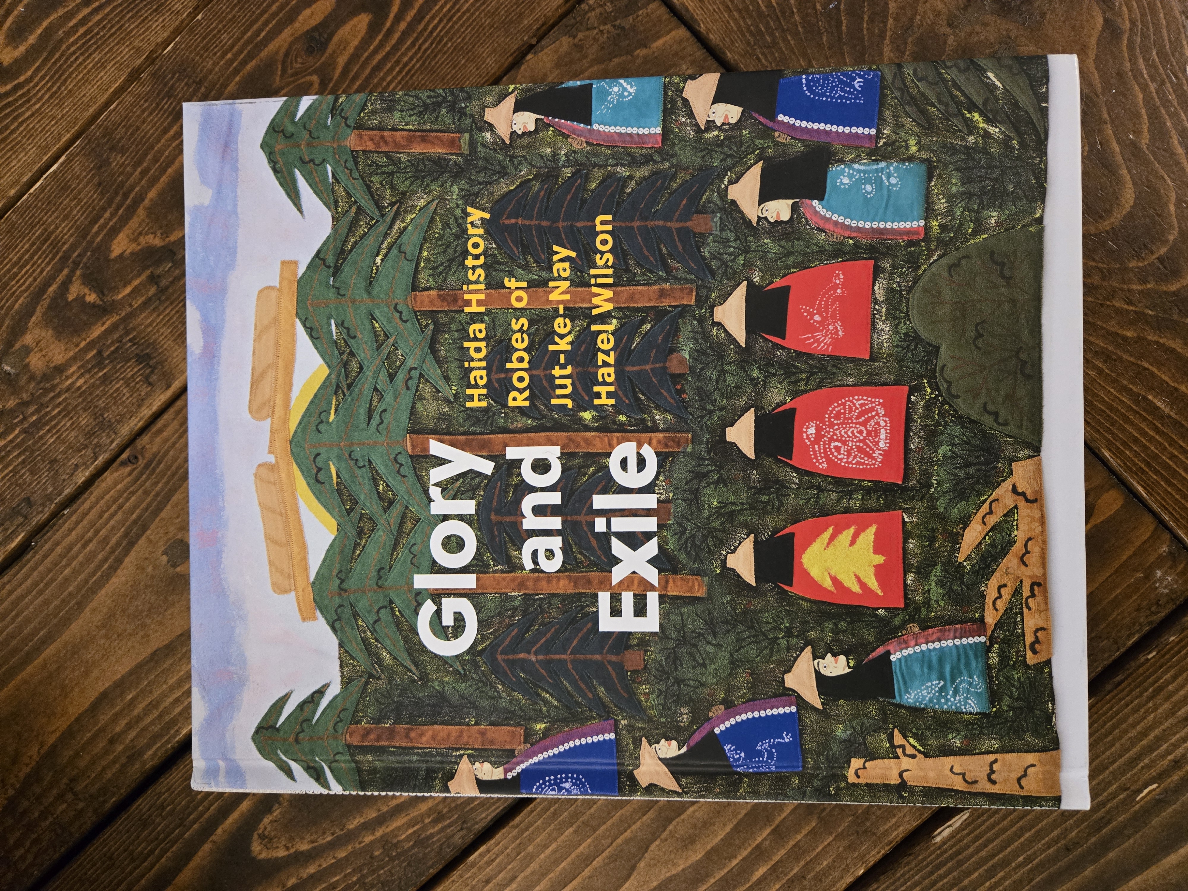 Book cover titled “Glory and Exile: Haida History Robes of Jut-ke-Nay Hazel Wilson,” featuring illustrated figures in robes among tall trees.