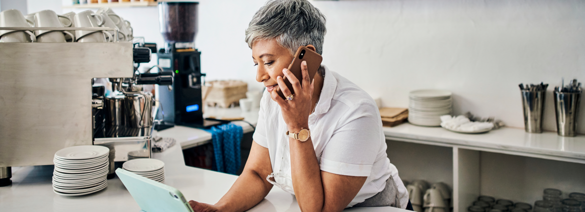 Woman with grey hair wearing a watch using a mobile device looking at a tablet device